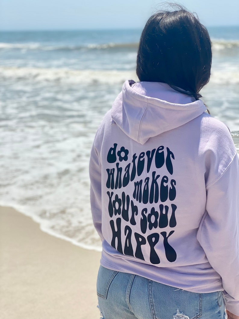 May include: A lavender hoodie with the text "do whatever makes your soul happy" in a retro font on the back.