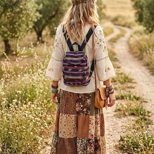 May include: A cream-colored long-sleeve blouse with floral embroidery, a multi-colored striped backpack, a brown leather crossbody bag, and a long patchwork skirt featuring various floral and solid brown fabric panels with brown sandals.