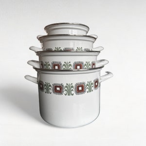 May include: A set of four white enamel pots with a green and orange geometric pattern. The pots are stacked on top of each other.