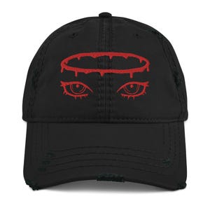 May include: Black distressed baseball cap with a red embroidered design of a halo and eyes.