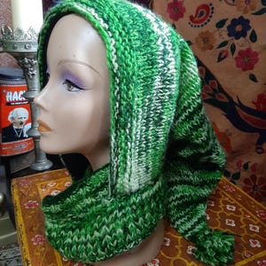 May include: Green and white striped knitted hooded scarf with a tassel. The scarf is made of a soft, warm yarn and is perfect for keeping you warm in the winter.