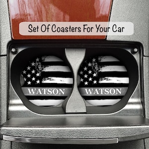 May include: Set of two black and white car coasters with a distressed American flag design and the name "WATSON" printed on each coaster.