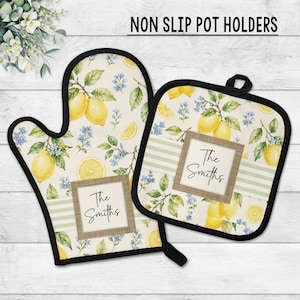 May include: A non-slip oven mitt and square pot holder set featuring a lemon and blue flower pattern on a cream background. Each piece has a central rectangular label with a wood-look border and the text The Smiths in black script.