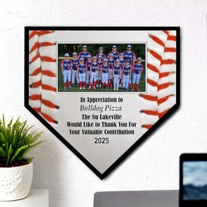 May include: A black and white baseball home plate with red and white stripes. A framed photo of a youth baseball team is in the center. The text "In Appreciation to Bulldog Pizza The 8u Lakeville Would Like to Thank You For Your Valuable Contribution 2025" is below the photo.
