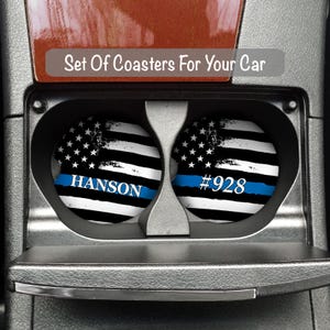 Peut inclure: Deux dessous-de-verre de voiture noirs et blancs avec une ligne bleue et un motif de drapeau am&eacute;ricain vieilli. Un dessous-de-verre porte le texte "HANSON" et l'autre le texte "#928".