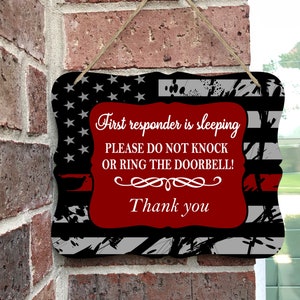 May include: A red, white, and blue American flag sign with the text "First responder is sleeping, PLEASE DO NOT KNOCK OR RING THE DOORBELL! Thank you".