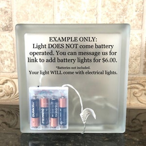 Puede incluir: Un bloque de vidrio esmerilado con una fuente de luz que funciona con pilas. La fuente de luz funciona con cuatro pilas AA Duracell. El texto en el bloque indica que la luz no funciona con pilas.