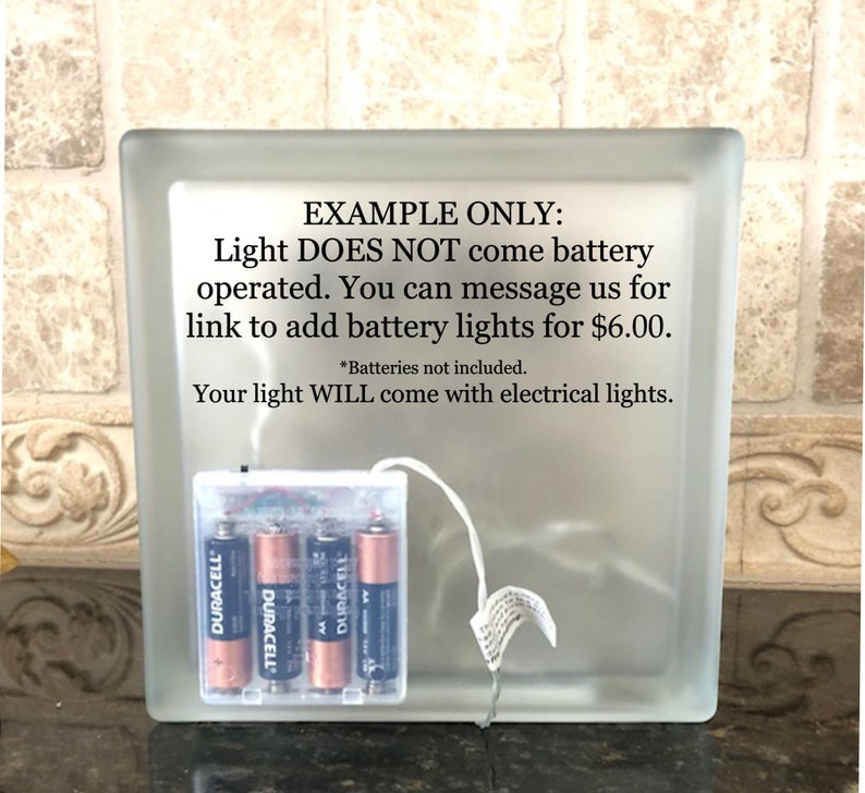 Puede incluir: Un bloque de vidrio esmerilado con una fuente de luz que funciona con pilas. La fuente de luz funciona con cuatro pilas AA Duracell. El texto en el bloque indica que la luz no funciona con pilas.