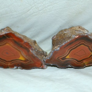 May include: Two halves of a geode with a red, orange, and brown agate pattern. The geode is cut in half and shows the intricate layers of the agate.