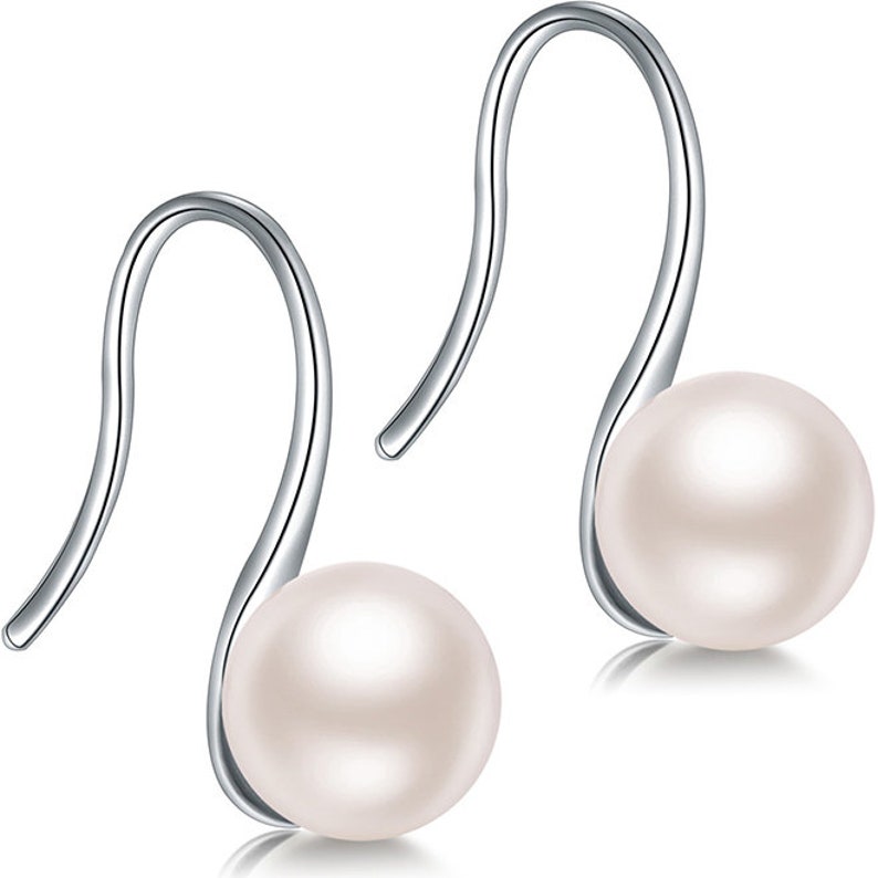 May include: A pair of silver dangle earrings with a white pearl on each earring.