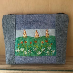Handgemaakte upcycled denim make-uptas met geborduurd paneel. Gratis blanco kaart.