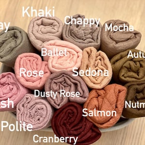 Op de afbeelding: Een verzameling opgerolde stoffen in verschillende kleuren, waaronder Clay, Khaki, Chappy, Mocha, Ballet, Rose, Dusty Rose, Blush, Polite, Cranberry, Salmon, Sedona, Autumn en Nutmeg. De kleurnamen worden in witte tekst weergegeven.