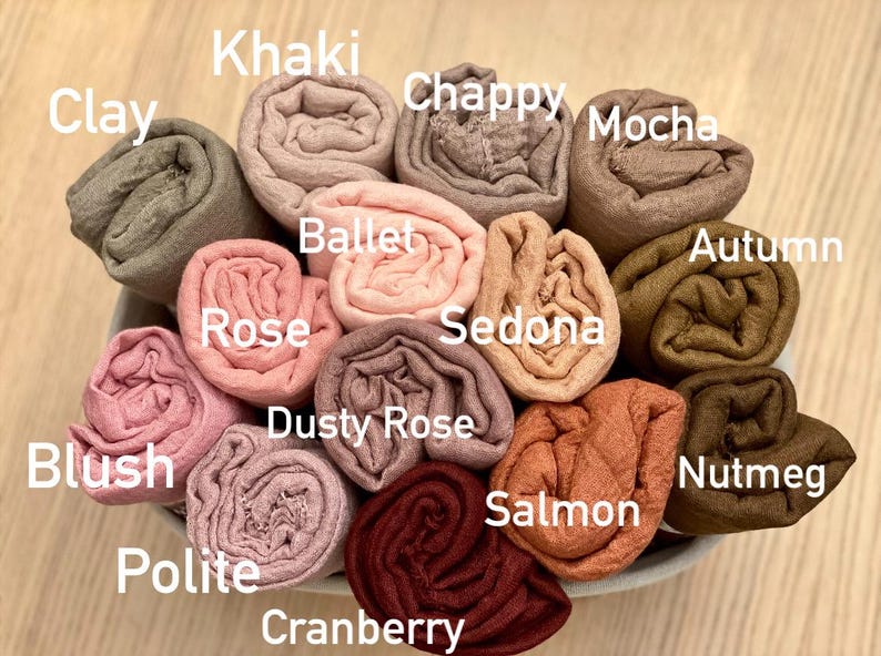 Op de afbeelding: Een verzameling opgerolde stoffen in verschillende kleuren, waaronder Clay, Khaki, Chappy, Mocha, Ballet, Rose, Dusty Rose, Blush, Polite, Cranberry, Salmon, Sedona, Autumn en Nutmeg. De kleurnamen worden in witte tekst weergegeven.