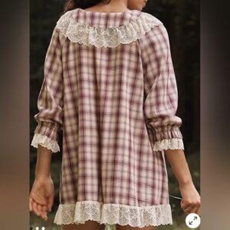 Op de afbeelding: Een geruite jurk in bordeaux, cr&egrave;me en beige tinten, met een kanten kraag, manchetten en zoom. De jurk heeft lange mouwen en een losse pasvorm, geschikt voor vrijetijdskleding.