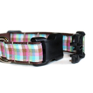 May include: A brown and pink plaid dog collar with a black plastic buckle and a silver D-ring.