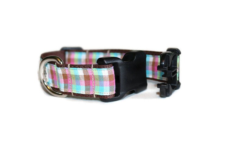 May include: A brown and pink plaid dog collar with a black plastic buckle and a silver D-ring.