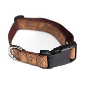 May include: A brown dog collar with a patterned design and a black plastic buckle.