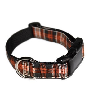 May include: A black and orange plaid dog collar with a black plastic buckle and a silver metal D-ring.