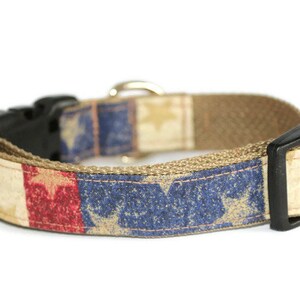 May include: A tan dog collar with a red, white, and blue distressed American flag print. The collar has a black plastic buckle.