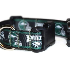 Puede incluir: Un collar de perro negro y verde con un anillo en D plateado y una hebilla de pl&aacute;stico negro. El collar presenta un patr&oacute;n repetido de logotipos de los Philadelphia Eagles en verde y blanco, incluyendo el nombre del equipo y un casco de f&uacute;tbol.