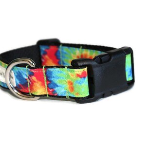 May include: A colorful tie-dye dog collar with a black plastic buckle and a silver metal D-ring.