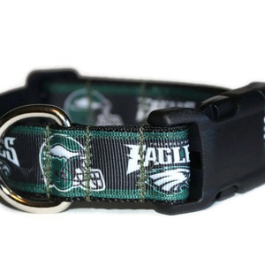 Puede incluir: Collar para perro negro y verde con un logotipo de los Philadelphia Eagles y la palabra "Eagles" impresa en &eacute;l. El collar tiene un anillo en D plateado y una hebilla de pl&aacute;stico negra.