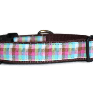 May include: A brown dog collar with a pink, blue, and green plaid pattern.