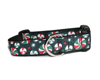 May include: A black dog collar with a green, red, and white peppermint candy design. The collar has a silver metal D-ring and a black plastic buckle.