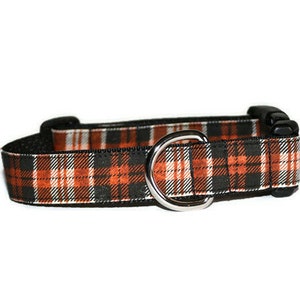 May include: A black and orange plaid dog collar with a silver metal D-ring.