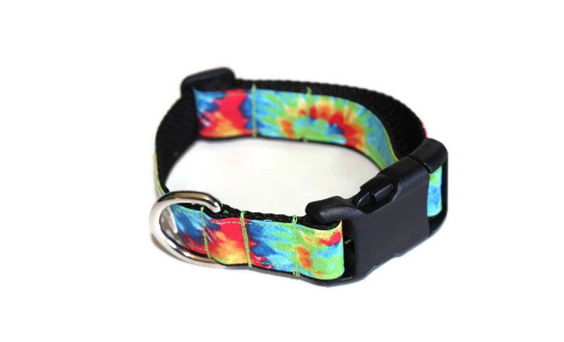 May include: A tie-dye dog collar with a black buckle and silver D-ring. The collar is made of a durable nylon material and features a colorful tie-dye pattern.