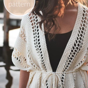 May include: A white crochet cardigan with a tie closure. The cardigan has a delicate openwork pattern and is worn over a black tank top.