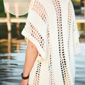 May include: A white crochet top with a lacy openwork design. The top has a loose fit and a wide neckline. The crochet pattern is visible throughout the garment.