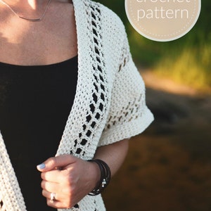 May include: A white crochet cardigan with a delicate openwork pattern. The cardigan is open in the front and has short sleeves.