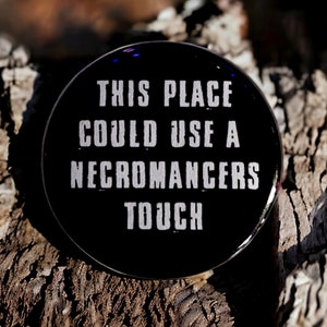 May include: A black button with white text that reads "This place could use a necromancers touch".
