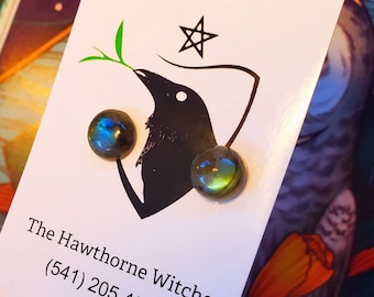 May include: A pair of iridescent green and blue labradorite gemstone earrings on a white card with a black crow illustration and the text "The Hawthorne Witches (541) 205 4238 Etsy: TheHawthorneWitches"