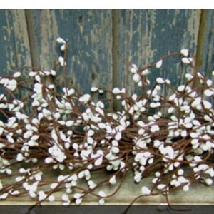 May include: A decorative garland featuring small white, teardrop-shaped berries clustered along brown stems. The garland is set against a weathered, blue-painted wooden background, creating a rustic aesthetic. Ideal for home decor and seasonal displays.