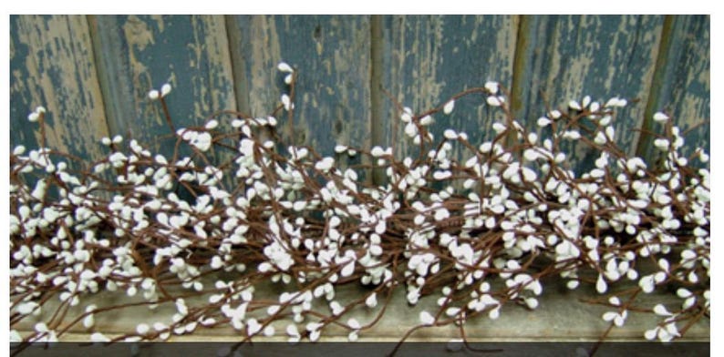 May include: A decorative garland featuring small white, teardrop-shaped berries clustered along brown stems. The garland is set against a weathered, blue-painted wooden background, creating a rustic aesthetic. Ideal for home decor and seasonal displays.