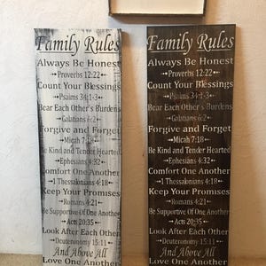 May include: Two rectangular wooden signs with the text "Family Rules" in a decorative font. The signs list various rules and inspirational quotes. One sign is white with black text, and the other is dark brown with white text.