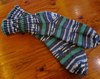 May include: A pair of striped socks in shades of blue, green, and white. The socks are knitted and have a ribbed texture.