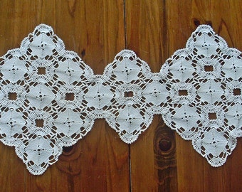 May include: White crocheted table runner with a delicate pattern of repeating squares. The runner is made of fine thread and has a lacy appearance.
