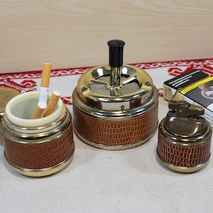 Op de afbeelding: Set van drie keramische mokken met een gespikkelde, matte afwerking. De mokken zijn in crème, lichtgrijs en donkergrijs. Elke mok heeft een minimalistisch ontwerp.