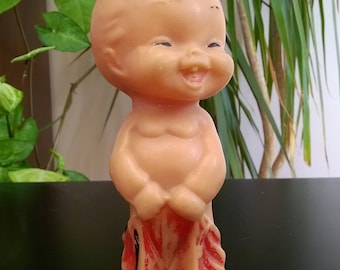 May include: A vintage rubber doll with a smiling face and red and white striped pants. The doll is made of a soft, pliable material and has a slightly weathered appearance.