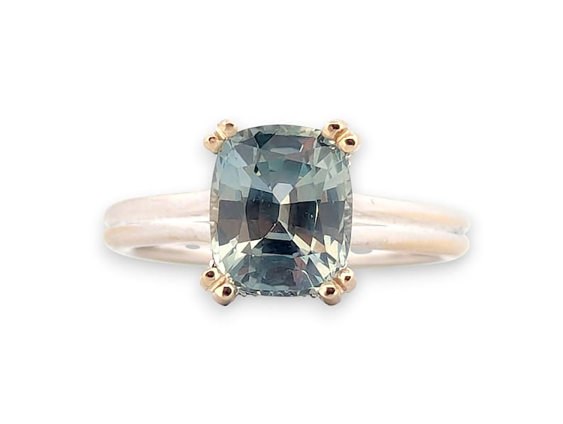 K&ouml;nnte beinhalten: Ein goldener Ring mit einem gr&uuml;nen Edelstein im Kissen-Schliff, der in einer Vier-Kralle-Fassung sitzt.