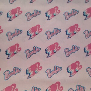 May include: Pink fabric with a repeating pattern of the word "Barbie" in a blue and pink font with a stylized image of a woman's face.