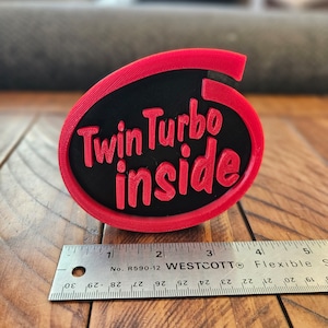 May include: A red and black 3D printed emblem with the text "Twin Turbo inside".