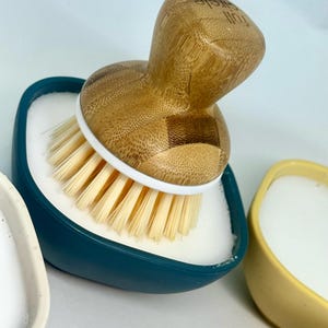以下が含まれることがあります： 白の石鹸皿と木製のハンドルが付いた竹製のブラシが付いた、ティールブルーの食器用洗剤ディスペンサー。ハンドルには「full circle」という文字が刻まれています。