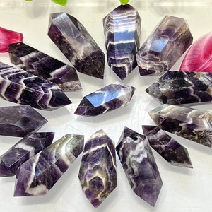 May include: A collection of 12 amethyst chevron points, each with a unique pattern of purple and white stripes. The points are arranged in a circle on a white surface.