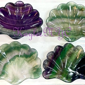 May include: Four fluorite shell dishes in various shades of green, purple, and white. The shells are carved from natural fluorite and have a smooth, polished finish.