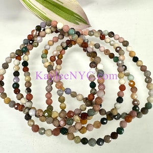 May include: A set of multi-colored gemstone bracelets with faceted beads. The bracelets are made of various stones, including pink, green, brown, and white.