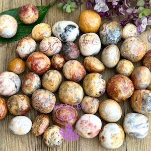 May include: A collection of tumbled agate stones in various shades of brown, white, and red. The stones have a swirling, banded pattern.